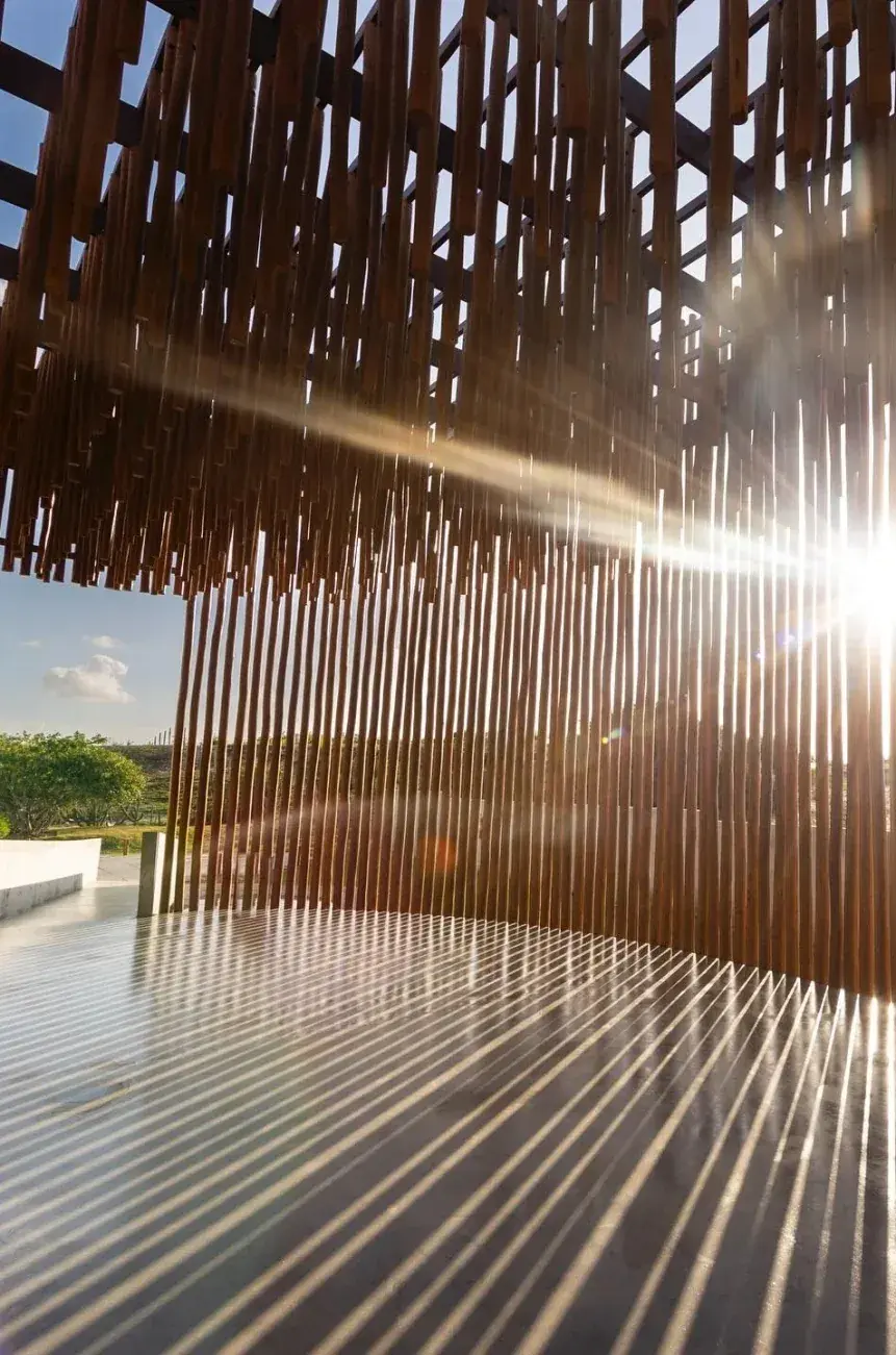 Interior da capela de troncos, com o sol entrando entre as madeiras